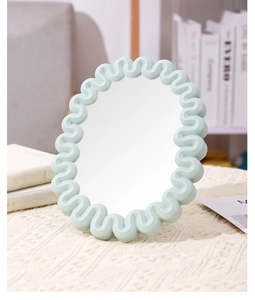 Detail of light blue wave frame vanity mirror on a soft beige knitted surface