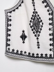 Detailed view of black ethnic embroidery on off-white cotton linen sleeveless top fabric