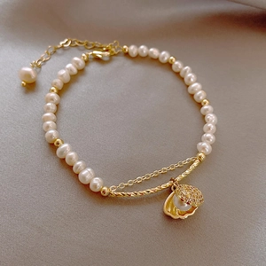 Detailed macro of baroque pearl bracelet with gold shell charm and adjustable link chain