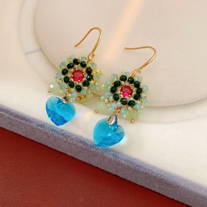 Dettaglio di orecchini vintage con gemme rosse e ciondoli a cuore in cristallo azzurro