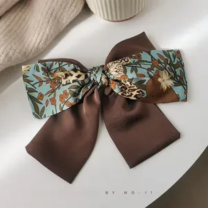 Detail of vintage bow hair tie with floral satin and ribbed dark brown fabric textures