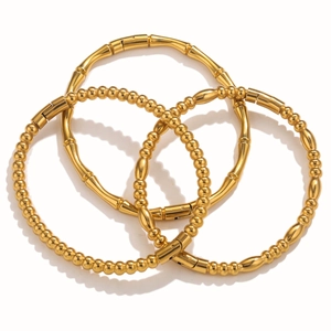 Gedetailleerd macro-aanzicht van een 3-delige set gouden bamboe- en kralenarmbanden
