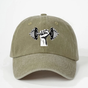 Detail view of washed cotton fabric and embroidered dumbbell graphic on an olive baseball cap