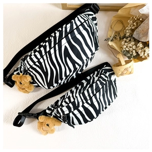Macro shot of zebra pattern canvas waist bags in two sizes with plush bear charms