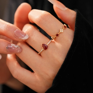 Macro shot of 18k gold plated clover and red heart gemstone rings on model finger