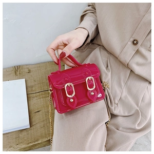 Macro detail of rose red jelly mini satchel featuring dual gold buckles and glossy PVC texture