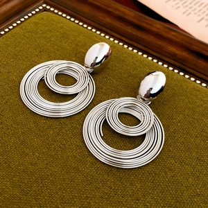 Close-up of geometric silver layered hoop earrings on a green velvet jewelry tray