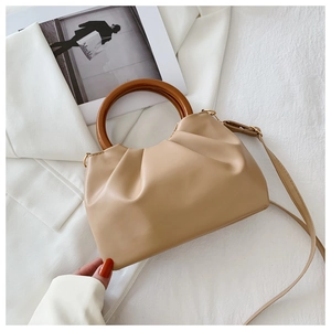 Detail of khaki pleated dumpling bag featuring unique wooden handle and leather texture