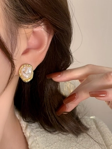Close-up of elegant gold irregular pearl ear clip on model ear for vintage style