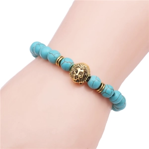 Detailed view of turquoise bead bracelet with a gold lion head charm on a hand model