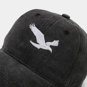 Macro shot of high-quality white eagle embroidery on washed gray cotton baseball cap