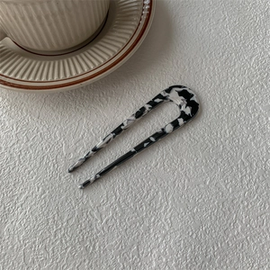 Épingle à cheveux en U avec motif marbré noir et blanc sur un fond minimaliste chic