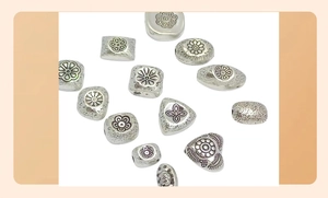 Detailed view of silver embossed metal beads in various shapes for DIY jewelry making
