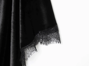 Detailansicht des schwarzen Samtkleides mit zarter Spitze und eleganter Satin-Oberfläche