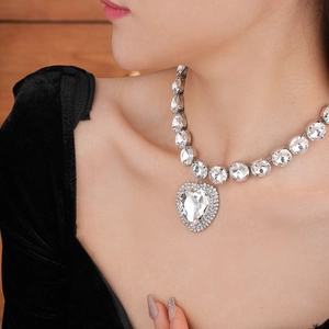 Close-up of a silver heart-shaped necklace set with sparkling crystals on a female model