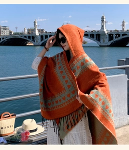 Bohemian hooded shawl with heart pattern and fringe, worn by a model in outdoor travel setting