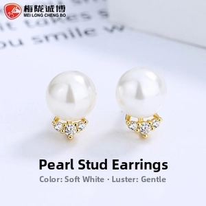 Macro shot of minimalist pearl stud earrings with zircon accents and gold plating