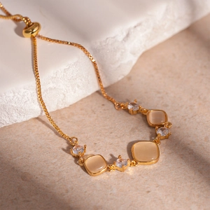 Vue détaillée de la pierre œil de chat carrée et du zircon sur le bracelet doré réglable