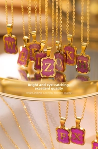 Detail of gold titanium necklaces with purple glitter pendants and gold letter charms