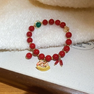 Dettaglio del bracciale di agata rossa con ciondolo a forma di cavallo a dondolo dorato