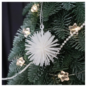 Sparkling white starburst Christmas ornament hanging on a festive tree with warm lights
