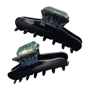 Detail showing two dark green marble pattern acetate hair claws with sturdy metal spring