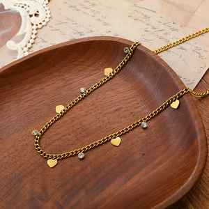 Elegant gold titanium necklace with heart charms and cubic zirconia on vintage wood