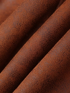 Gros plan du tissu de la veste en simili mouton montrant le grain du cuir marron rouille