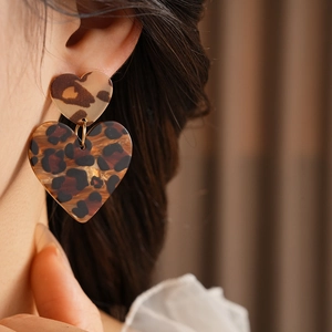 Close-up of stylish leopard print heart earrings worn by a model in soft lighting