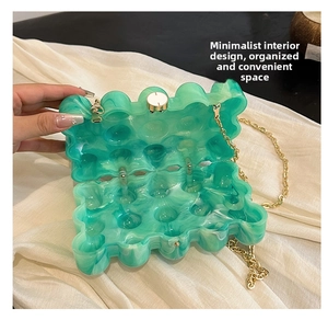 Détail de l'intérieur du sac en acrylique vert avec texture ondulée et chaîne dorée