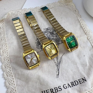 Detailed shot of three vintage square women's gold watches with pearl white, gold, and green dials