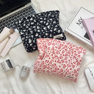 Close-up of corduroy leopard print makeup bags with heart patterns on soft fabric background