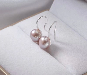 Macro shot of elegant pink-purple natural pearls on S925 silver hooks in jewelry box