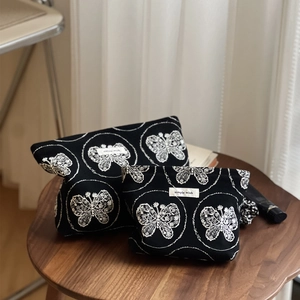 Détails de broderies papillon blanc et motifs sur trousses de maquillage en toile