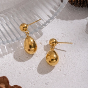 Minimalist gold teardrop earrings with polished finish on a modern stone background