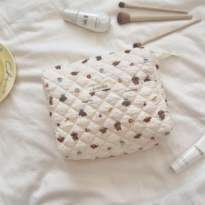 Close-up of quilted cotton makeup bag with bear prints and high-end skincare props