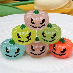 Close-up of colorful resin luminous pumpkin ornaments with carved faces on a white plate