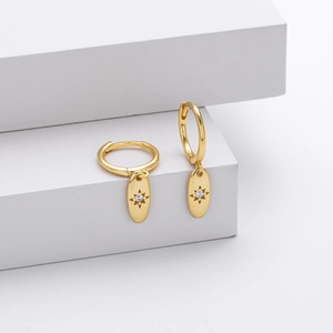 Detail of gold oval drop earrings with starburst pattern and small zircon stone