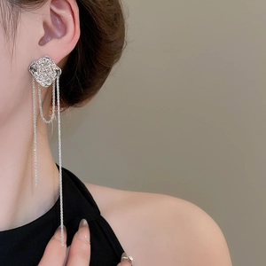 Close-up of silver irregular flower earrings with long metal tassel chains on a model