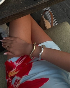 Close-up of irregular fluid gold and silver bangles with a matching ring for women