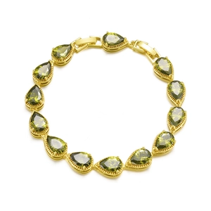 Macro shot of gold bracelet with pear-cut olive green cubic zirconia stones