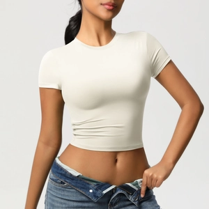Slim fit off-white athletic crop top paired with blue jeans in a studio shot