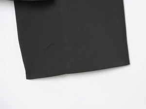 Détail du tissu de blazer noir montrant la texture sergée fine et les coutures nettes