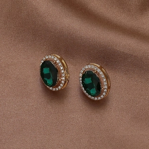 Détail macro de boucles d'oreilles émeraude vintage avec cadre doré sur satin brun