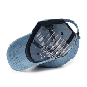 Detail of denim baseball cap interior showing 100% cotton label and metal buckle