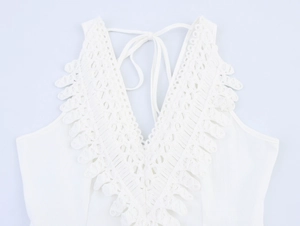 Detail of deep V-neckline with intricate lace embroidery on white vacation dress