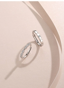 Close-up of S925 sterling silver couple rings with white zircon on light pink background