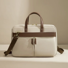 Detail of a dual-tone beige and brown shoulder bag featuring leather tassels and zippers