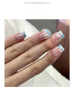 Detail of short square press-on nails with blue French tips and white flower patterns