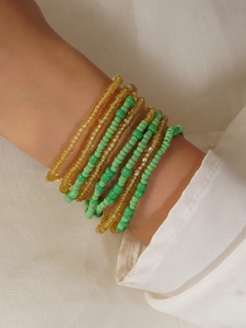 Close-up of bohemian layered yellow and green seed bead waist chain on white fabric